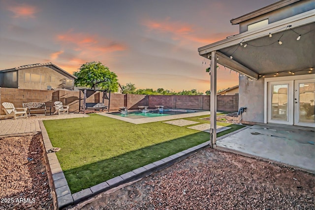 yard at dusk with a fenced backyard, a fenced in pool, and a patio