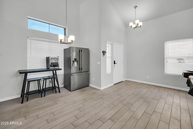 interior space featuring high vaulted ceiling, light wood-type flooring, and a notable chandelier