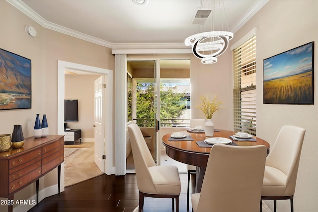 dining room with an inviting chandelier, ornamental molding, baseboards, and wood finished floors