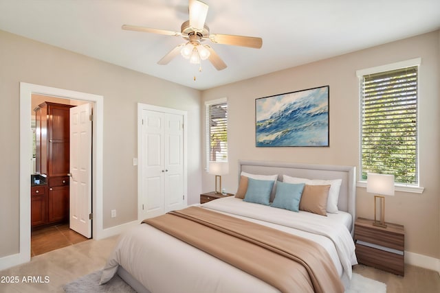 bedroom with ensuite bath, light carpet, baseboards, and multiple windows