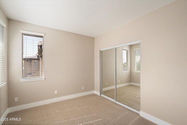unfurnished bedroom featuring carpet flooring, a closet, and baseboards