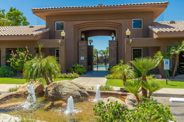 entrance to property with stucco siding, a gate, and a tiled roof