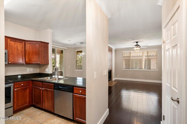 kitchen featuring crown molding, a fireplace, ceiling fan, appliances with stainless steel finishes, and a sink
