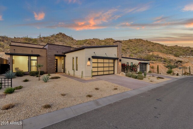 modern home with an attached garage, concrete driveway, and stucco siding