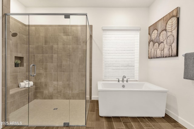 bathroom featuring a stall shower, a freestanding bath, baseboards, and wood tiled floor