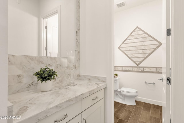 bathroom with toilet, wood tiled floor, visible vents, and vanity