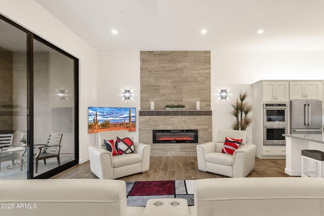 living room featuring recessed lighting, a tiled fireplace, and wood finished floors