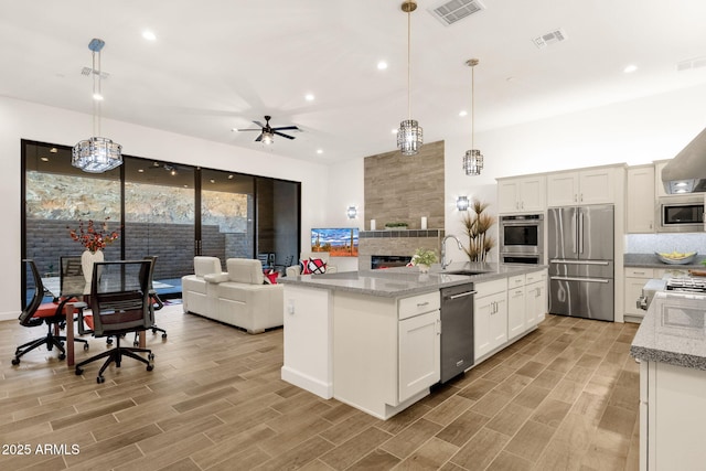 kitchen with open floor plan, stainless steel appliances, a sink, and visible vents