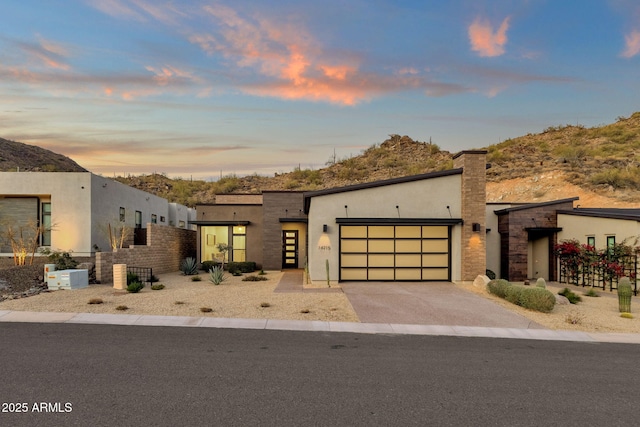 modern home with a garage, aphalt driveway, fence, and stucco siding