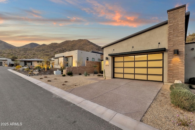 modern home featuring driveway, a garage, a mountain view, and stucco siding