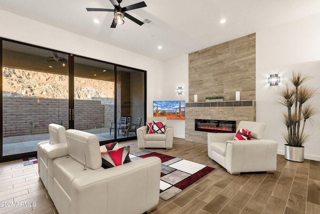 living room featuring recessed lighting, a ceiling fan, a tiled fireplace, and wood finish floors