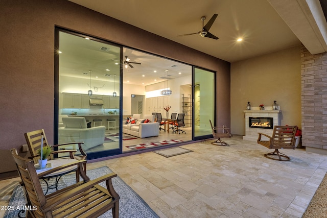 view of patio / terrace with ceiling fan and a glass covered fireplace