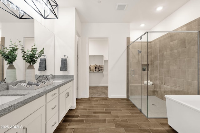 bathroom with a stall shower, wood finish floors, a sink, and double vanity