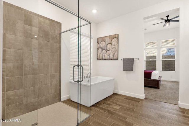 bathroom featuring a stall shower, baseboards, a ceiling fan, a soaking tub, and wood finish floors