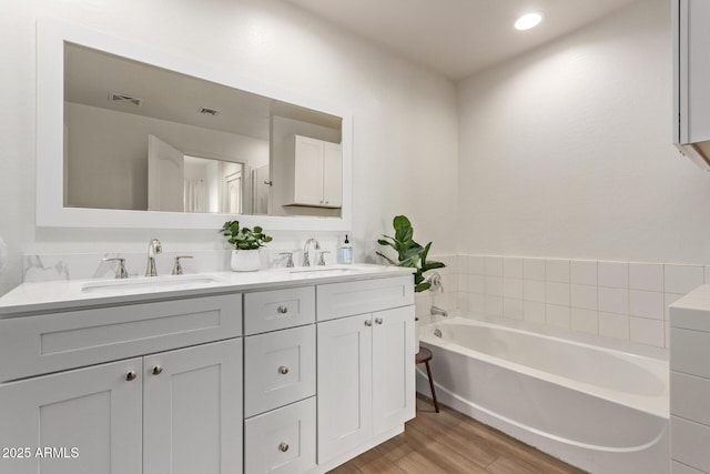 bathroom featuring wood-type flooring, vanity, and a tub