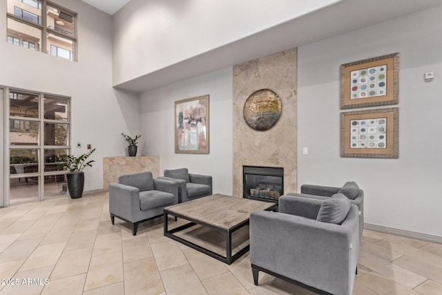 tiled living room featuring a fireplace and a towering ceiling