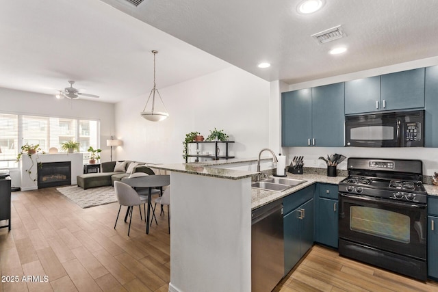 kitchen with kitchen peninsula, sink, black appliances, and blue cabinets