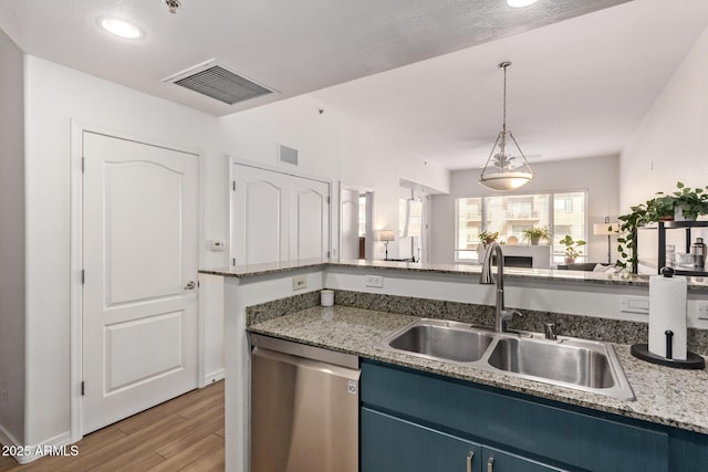 kitchen with stainless steel dishwasher, sink, blue cabinetry, decorative light fixtures, and light hardwood / wood-style floors