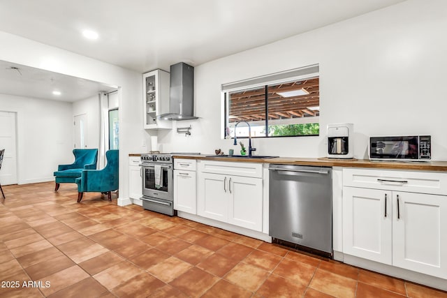 1451 E Brown Rd, Mesa, AZ 85203 - kitchen with glass insert cabinets, wall chimney range hood, white cabinetry, a sink, and appliances with stainless steel finishes