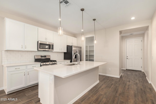 kitchen with decorative light fixtures, tasteful backsplash, white cabinetry, a kitchen island with sink, and stainless steel appliances