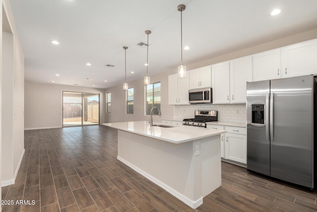 kitchen featuring sink, white cabinetry, hanging light fixtures, an island with sink, and stainless steel appliances