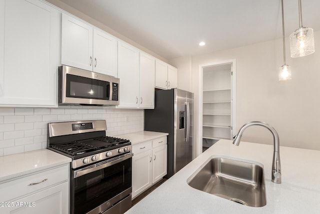 kitchen with pendant lighting, sink, appliances with stainless steel finishes, tasteful backsplash, and white cabinets