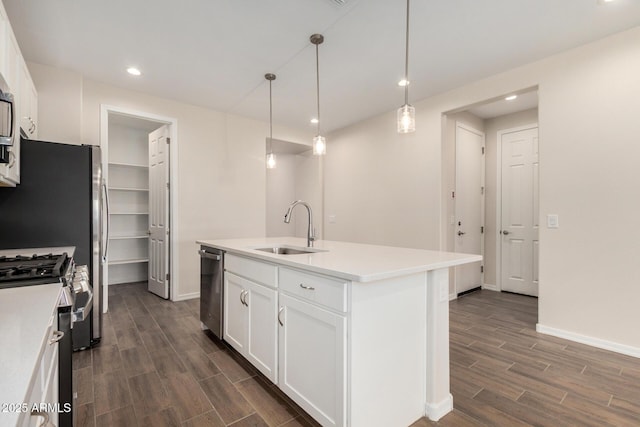 kitchen with pendant lighting, sink, appliances with stainless steel finishes, an island with sink, and white cabinets