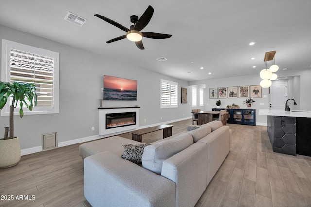 31435 N 130th Ave, Peoria, AZ 85383 - living area featuring a glass covered fireplace, light wood finished floors, visible vents, and recessed lighting
