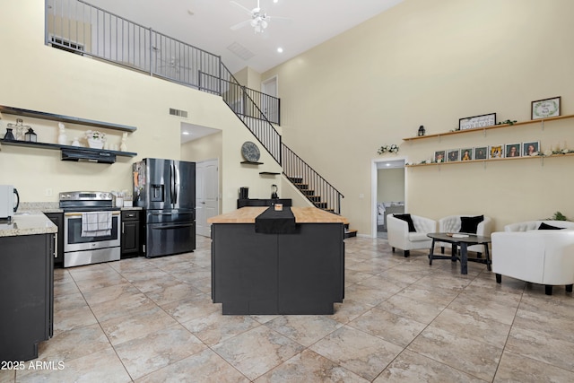 living area featuring visible vents, a high ceiling, ceiling fan, and stairs