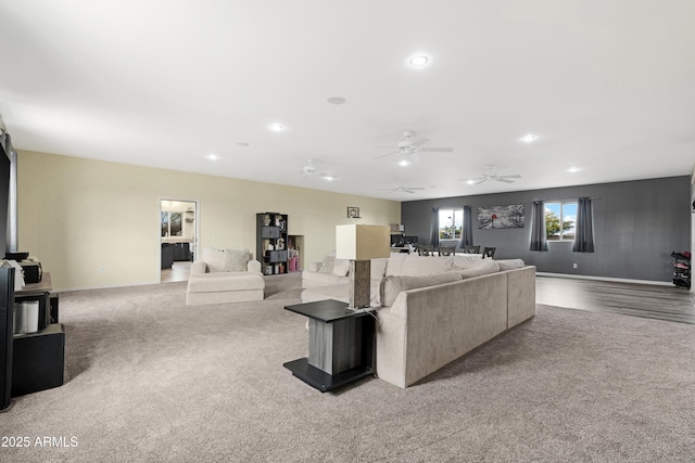 living area featuring baseboards, a ceiling fan, and carpet flooring