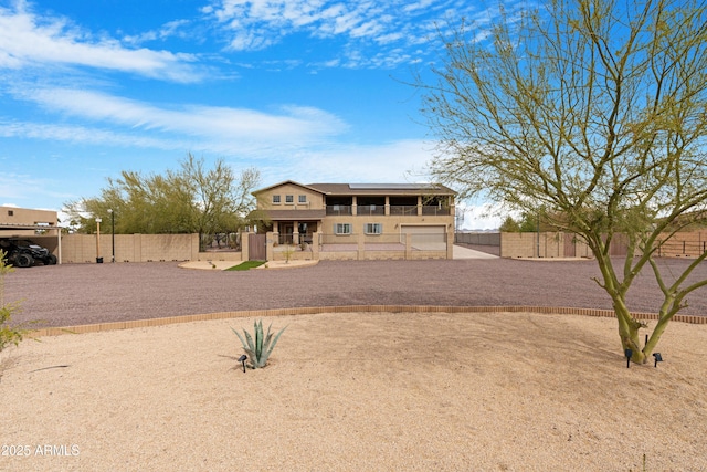 view of front facade with roof mounted solar panels, fence private yard, and a gate