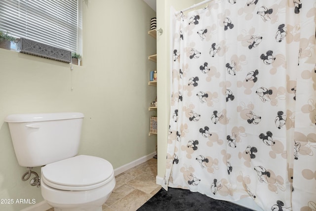 bathroom featuring a shower with shower curtain, toilet, and baseboards