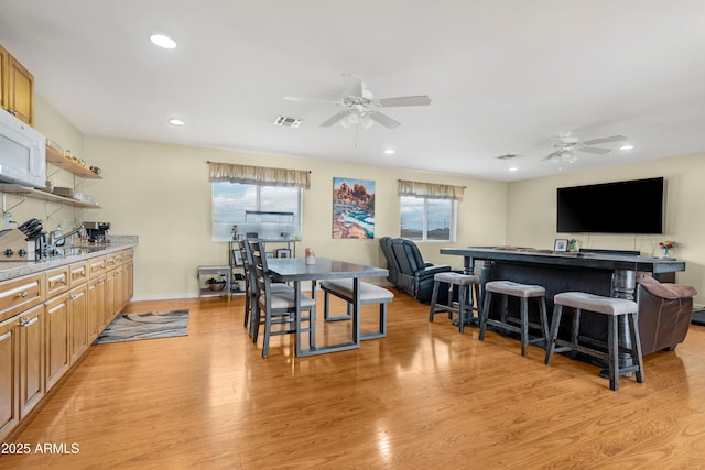 kitchen with visible vents, open floor plan, ceiling fan, and light wood finished floors