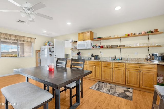 kitchen with open shelves, visible vents, white appliances, and light wood finished floors