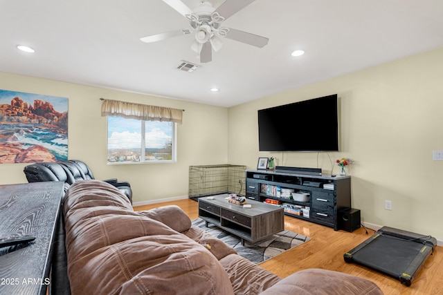 living room featuring visible vents, baseboards, ceiling fan, and light wood finished floors