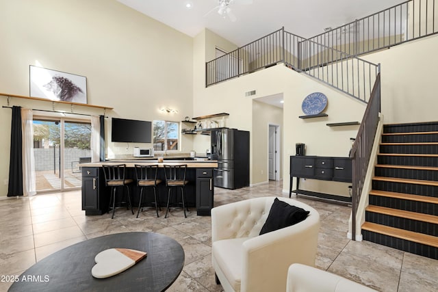 living area with stairway, a healthy amount of sunlight, a ceiling fan, and visible vents