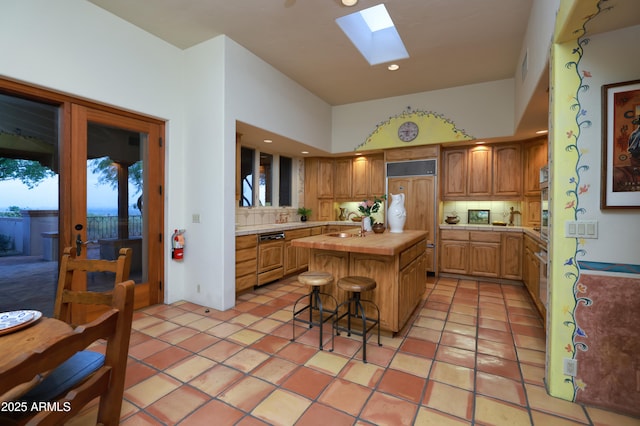 4885 N Via De La Granja, Tucson, AZ 85718 - kitchen with a skylight, a kitchen island, decorative backsplash, paneled appliances, and a kitchen breakfast bar