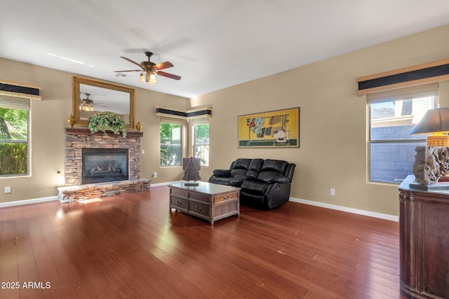 living area with a ceiling fan, hardwood / wood-style floors, a fireplace, and baseboards