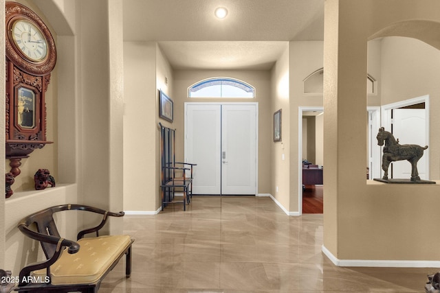 foyer entrance featuring arched walkways and baseboards