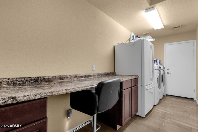 clothes washing area featuring washer and clothes dryer, a textured ceiling, and an office area