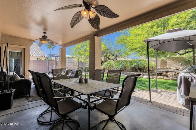 view of patio featuring outdoor dining space, a fenced backyard, and a ceiling fan