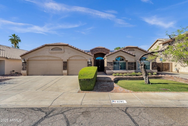 mediterranean / spanish house with an attached garage, driveway, stucco siding, and a tiled roof