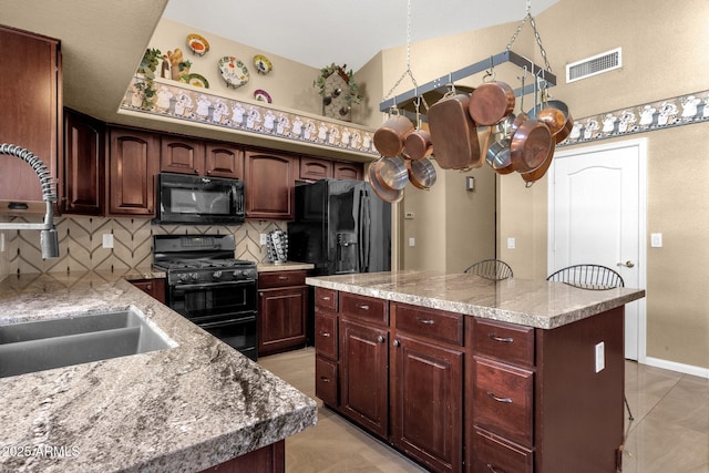 kitchen with black appliances, a sink, backsplash, a kitchen island, and light countertops
