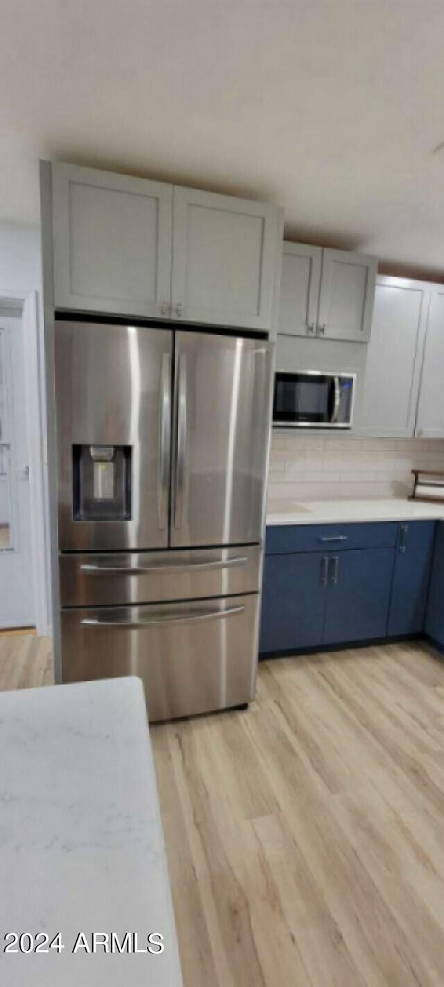 kitchen with light hardwood / wood-style flooring, stainless steel appliances, and blue cabinetry