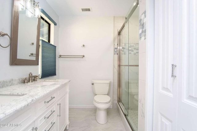 bathroom with vanity, toilet, and a shower with door