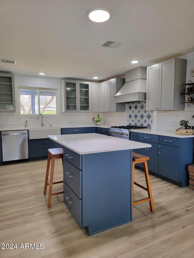 kitchen featuring a kitchen bar, appliances with stainless steel finishes, a kitchen island, and custom exhaust hood