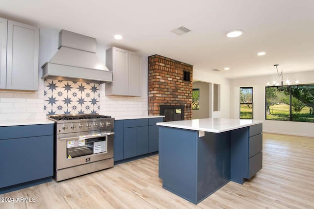 kitchen featuring custom range hood, tasteful backsplash, high end stove, a center island, and light hardwood / wood-style flooring