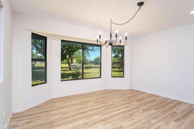 unfurnished dining area with light hardwood / wood-style flooring and a notable chandelier