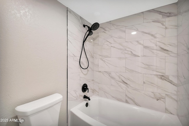 bathroom with tiled shower / bath combo and toilet