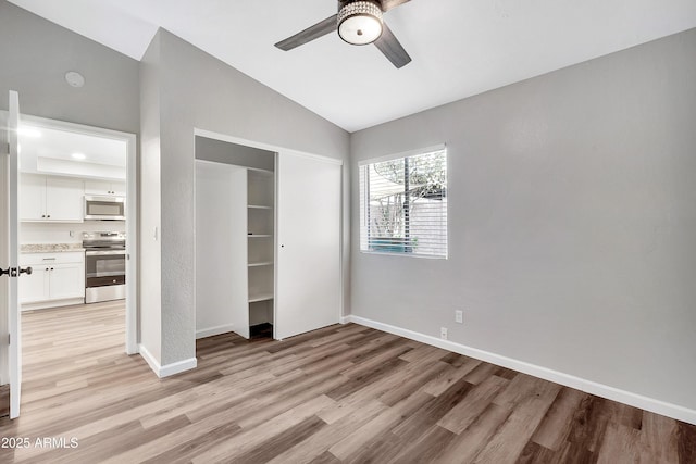 unfurnished bedroom featuring light hardwood / wood-style floors, vaulted ceiling, and ceiling fan